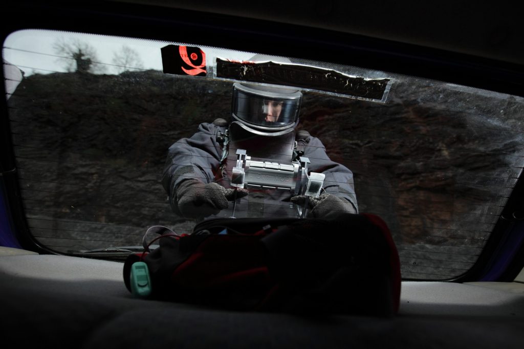 An EOD operator deploying DemiMod disruptor against an IED in a vehicle