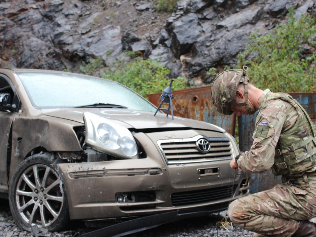 An operator positions a Pluton shaped charge against a car bonnet (hood)