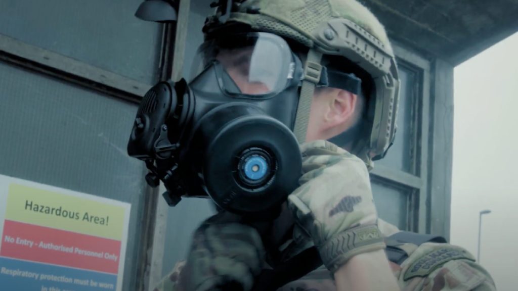 An operator prepares for vertical assault, equipping himself with Avon Protection FM54 Tactical Respirator