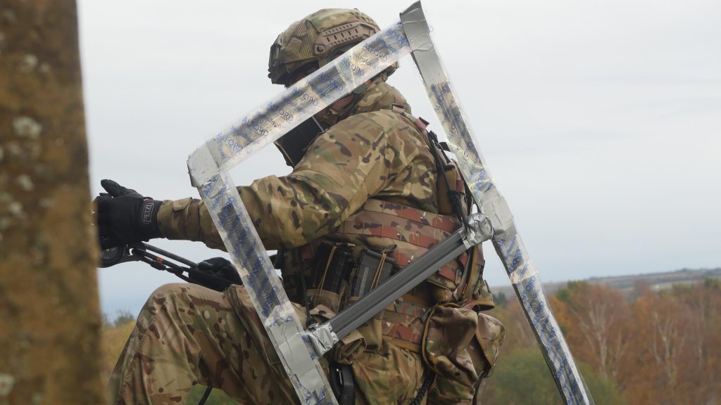 An operator ropes down a building carrying Alford Strip breaching charge