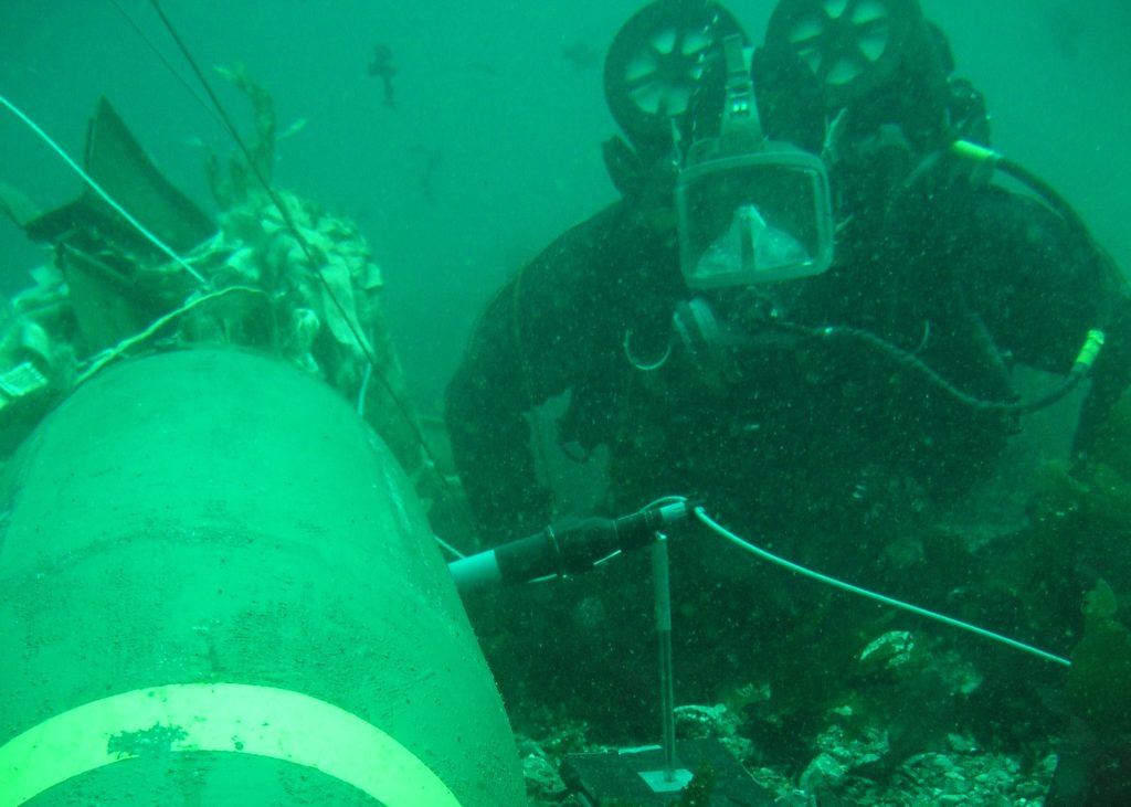 A diver positions a Vulcan shaped charge against an underwater UXO